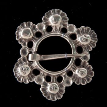 Brooch with a circle of masques surrounding a ring with a loose pin - Norwegian Metalworking