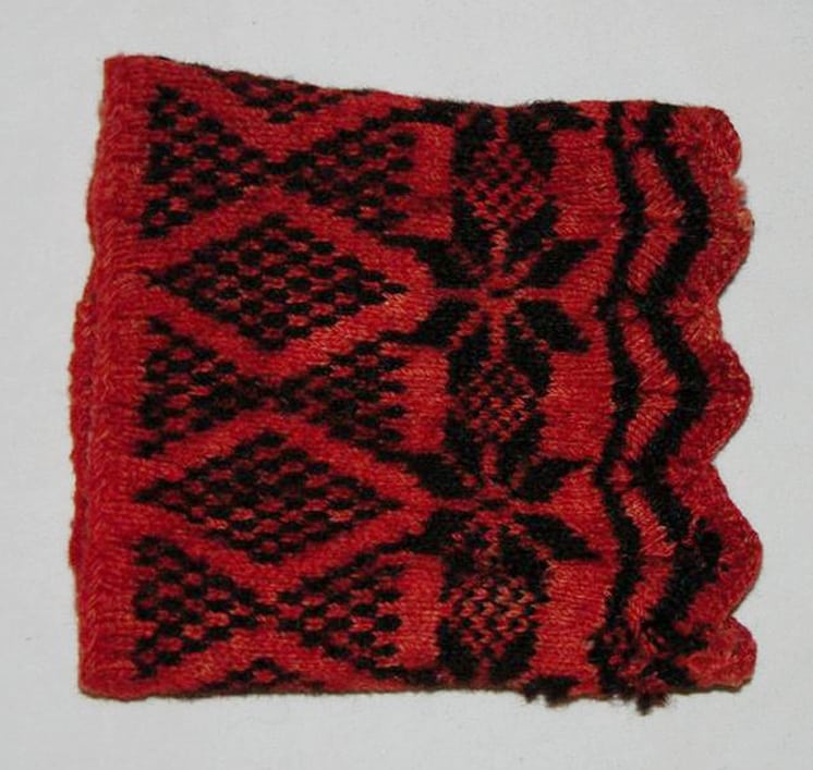 Wrist warmers hand-knit using what appears to be vegetable dyed red and black sheep wool