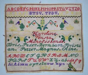 Alphabet sampler (navneduk) was done in bright colored cross-stitches on a fairly coarse canvas backing - Textiles