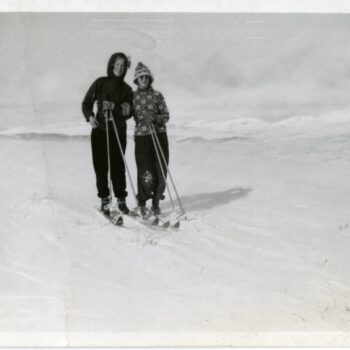 Two women pose while skiing.