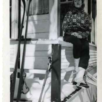 A woman sits on the porch in her ski gear. Possibly Nora Bernts