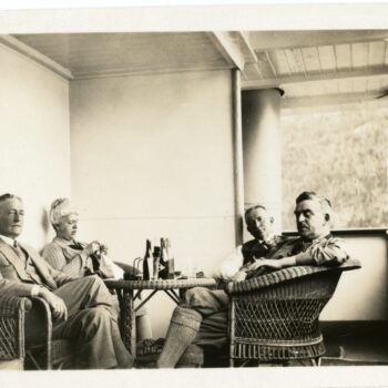 Four individuals sit at table on a porch.