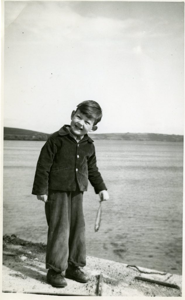 A small child, Miles Comwall, holds a fish.