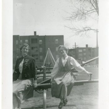 Two women on a teeter totter. One is wearing a bunad.