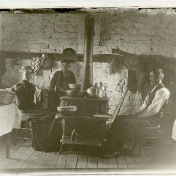 Man, woman, and child sit around stove.