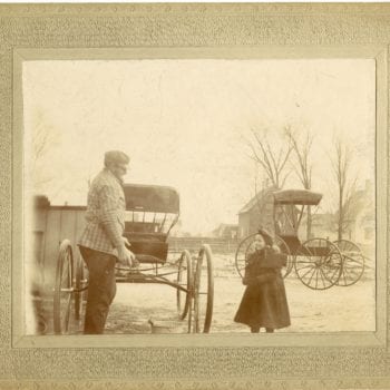 Man and young girl interact. Two buggies in the background.