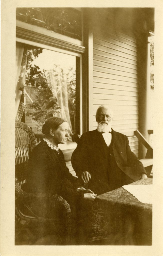 A man and woman sitting in chairs on porch.