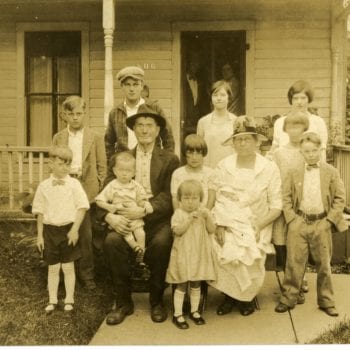 Grandparents and grandchildren pose for a photo outside of house.