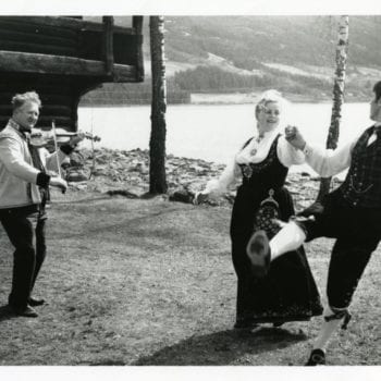 Man and woman dance in Norway with man playing instrument.