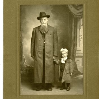 Older man and young child pose for a photo in a studio.