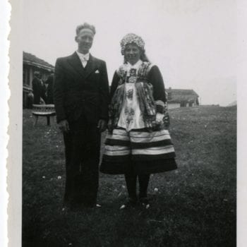 Man and woman pose for photo, woman in national dress.