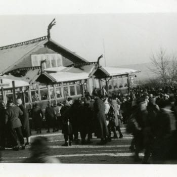 A large crowd gathers outside of building.