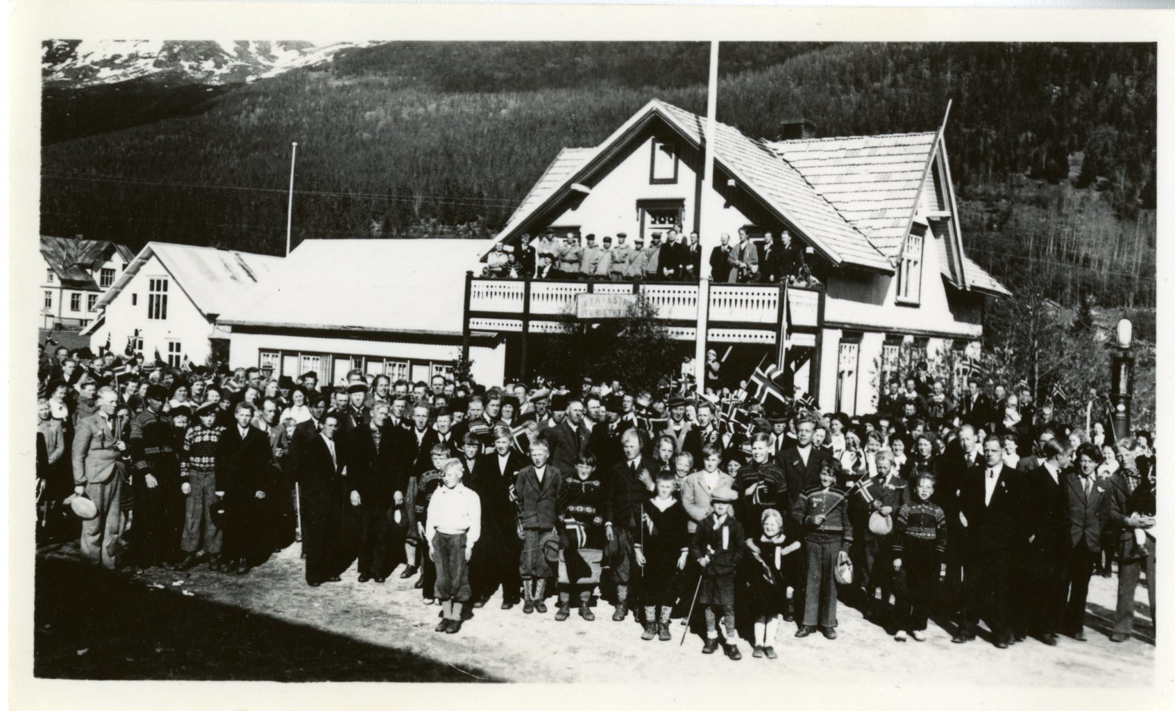 A large crowd poses for a photo outside of building.