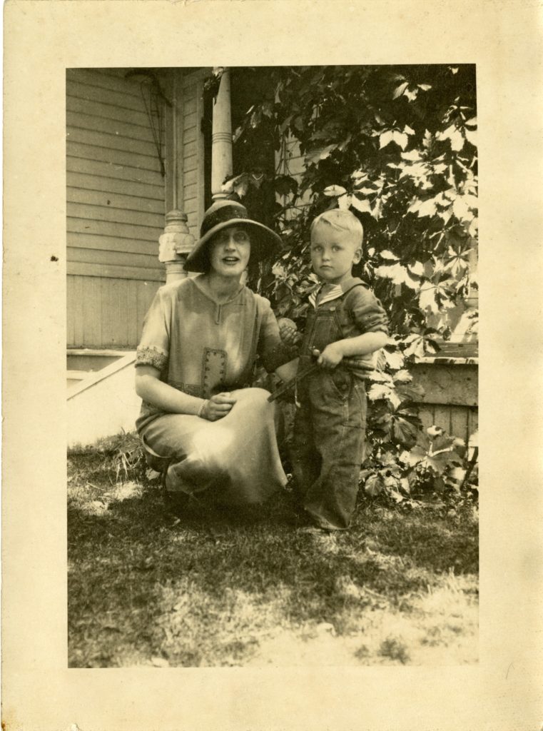 Woman and child pose for a photo outside of house.