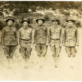 Seven men dressed in uniform stand in a line.