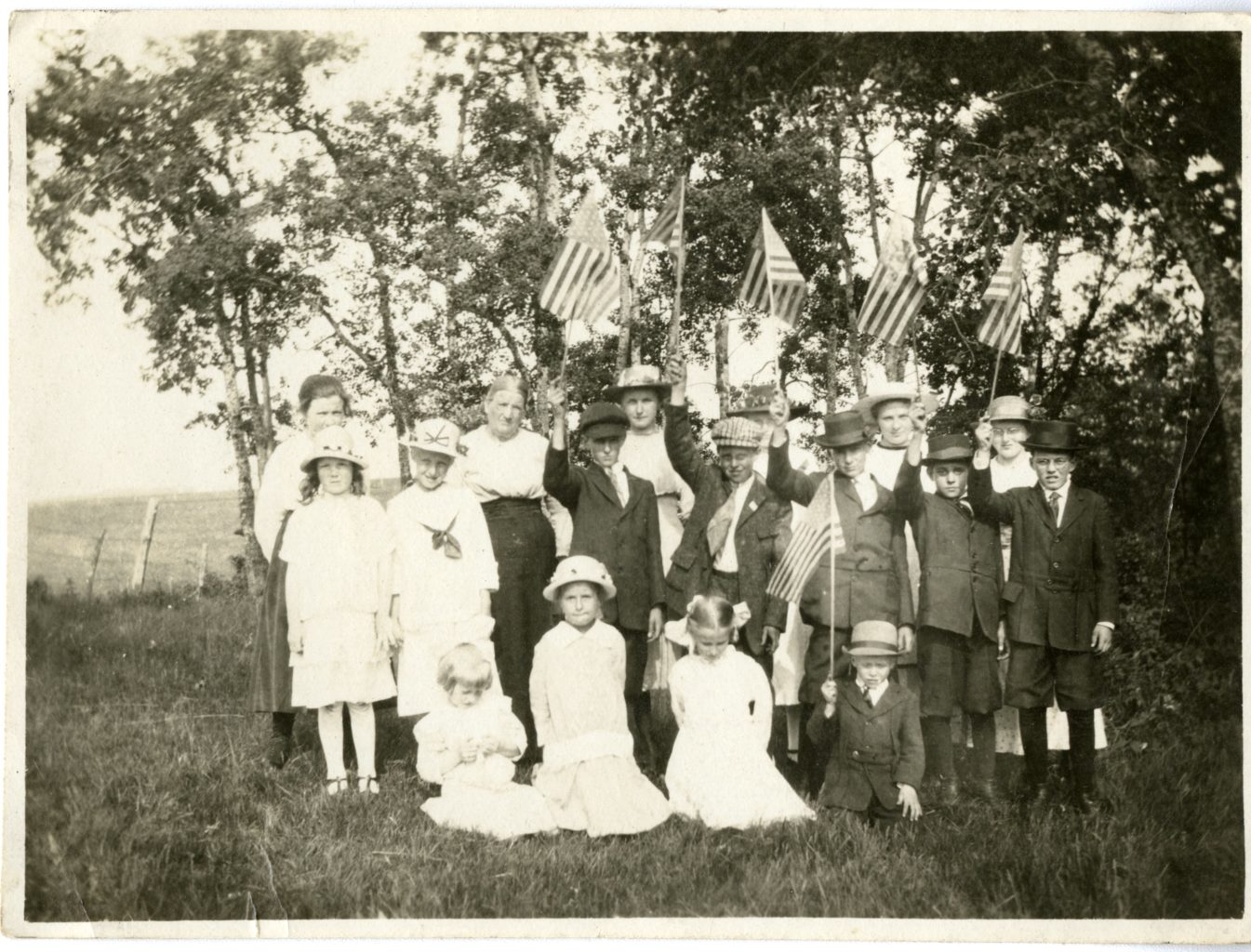 Group of children and one adult pose for a photo with American flags.