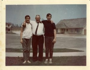 Father and two sons pose for photo outside of house.