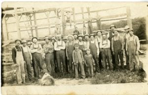 Group of men and boys gather for barn raising.