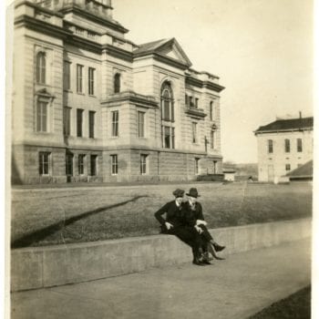 Two men sit outside of the Decorah Courthouse.
