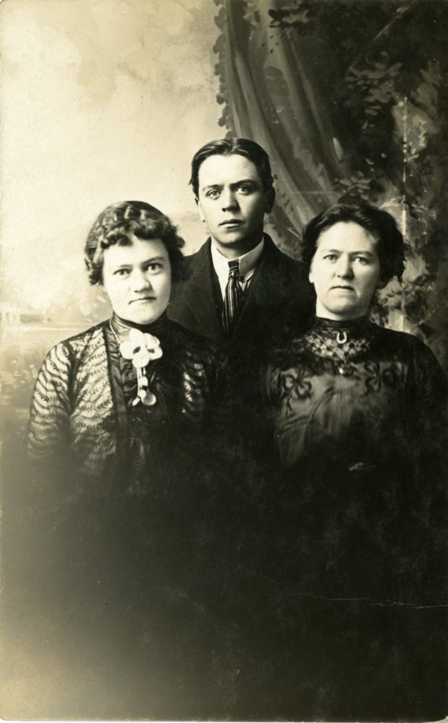 Two women and one man pose in a studio.